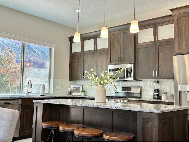 108 Trapper Cir Unit A, Springdale, UT 84767 - kitchen with stainless steel appliances, backsplash, dark brown cabinets, a kitchen island, and a textured ceiling