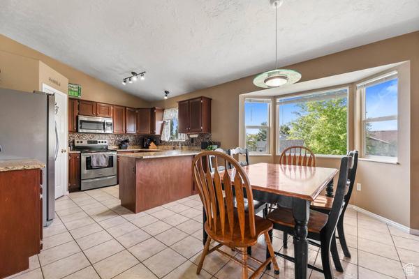 755 E 890 N, Tooele, UT 84074 - dining space with light tile patterned floors, lofted ceiling, track lighting, and baseboards