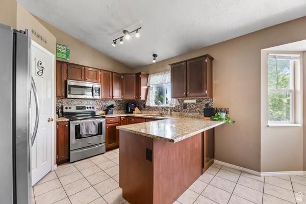 755 E 890 N, Tooele, UT 84074 - kitchen featuring stainless steel appliances, a peninsula, tasteful backsplash, light tile patterned floors, and lofted ceiling