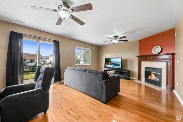 755 E 890 N, Tooele, UT 84074 - living area with ceiling fan, light wood-type flooring, a tile fireplace, and baseboards