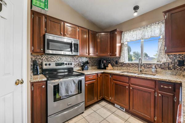 755 E 890 N, Tooele, UT 84074 - kitchen with stainless steel appliances, a sink, decorative backsplash, lofted ceiling, and light tile patterned floors