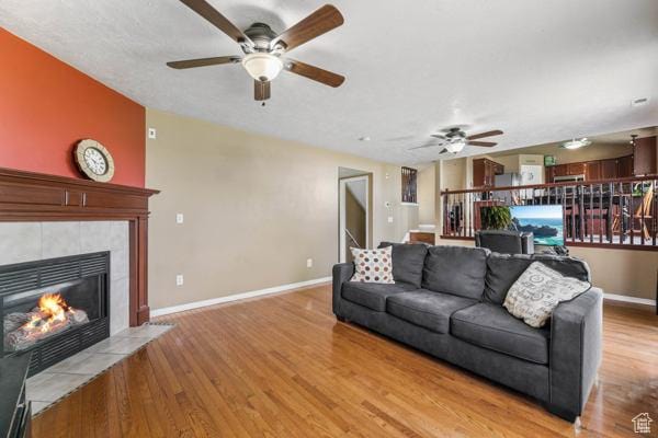 755 E 890 N, Tooele, UT 84074 - living area featuring a ceiling fan, a tiled fireplace, light wood-style floors, and baseboards