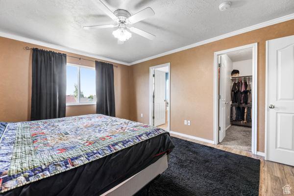 755 E 890 N, Tooele, UT 84074 - bedroom featuring a spacious closet, wood finished floors, crown molding, baseboards, and a textured ceiling