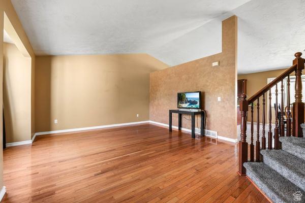 755 E 890 N, Tooele, UT 84074 - unfurnished living room featuring wood finished floors, baseboards, lofted ceiling, and stairs