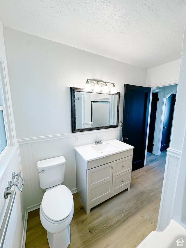 1797 N 5900 W, Warren, UT 84404 - bathroom featuring wood finished floors, a textured ceiling, toilet, vanity, and wainscoting