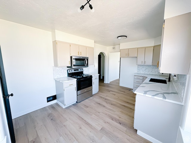 1797 N 5900 W, Warren, UT 84404 - kitchen with appliances with stainless steel finishes, decorative backsplash, light wood-style flooring, and a textured ceiling