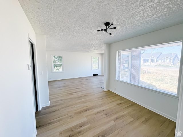 1797 N 5900 W, Warren, UT 84404 - unfurnished room with light wood finished floors, a textured ceiling, baseboards, and a chandelier