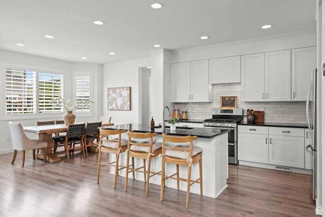 1314 W 1550 N, Lehi, UT 84043 - kitchen with stainless steel appliances, dark countertops, a breakfast bar, wood finished floors, and recessed lighting