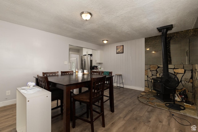 8750 W Helen Dr N, Magna, UT 84044 - dining area featuring baseboards, dark wood finished floors, a textured ceiling, and a wood stove