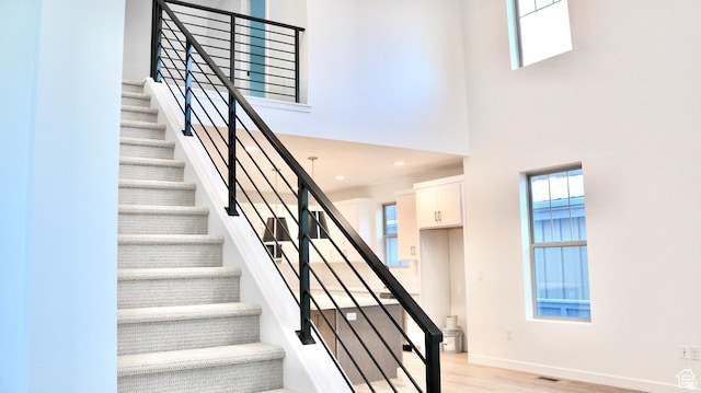 11208 S Easy Bee St Unit 268, South Jordan, UT 84009 - stairway with plenty of natural light, a high ceiling, wood finished floors, and baseboards