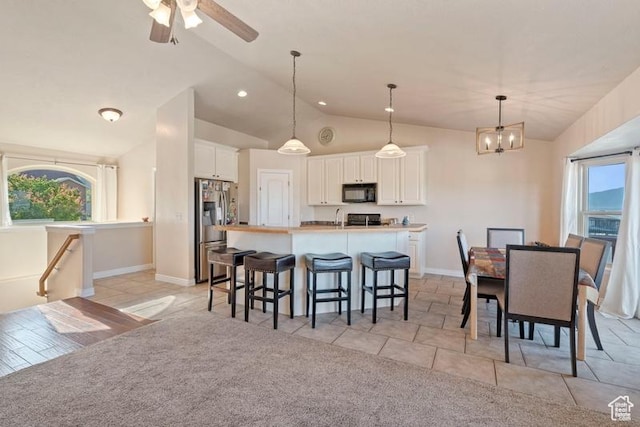 3972 S Lake Vista Dr, Saratoga Springs, UT 84045 - kitchen with black microwave, stainless steel fridge, a breakfast bar, white cabinets, and an island with sink