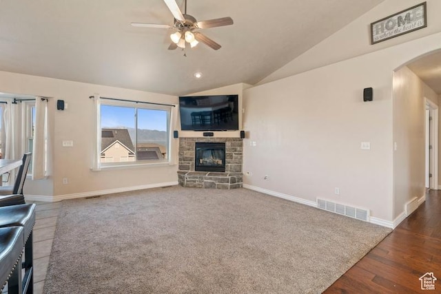 3972 S Lake Vista Dr, Saratoga Springs, UT 84045 - unfurnished living room featuring arched walkways, ceiling fan, lofted ceiling, a stone fireplace, and baseboards
