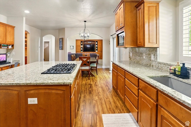 1926 N 1420 W, Provo, UT 84604 - kitchen featuring black gas stovetop, arched walkways, a center island, wood finished floors, and light stone countertops
