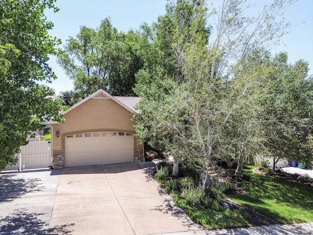1111 E Bench View Dr, Ogden, UT 84404 - obstructed view of property with stone siding, stucco siding, concrete driveway, a garage, and a gate