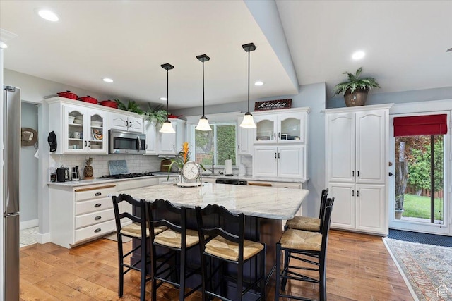 3272 N 175 W, North Ogden, UT 84414 - kitchen with appliances with stainless steel finishes, a breakfast bar, white cabinets, glass insert cabinets, and recessed lighting