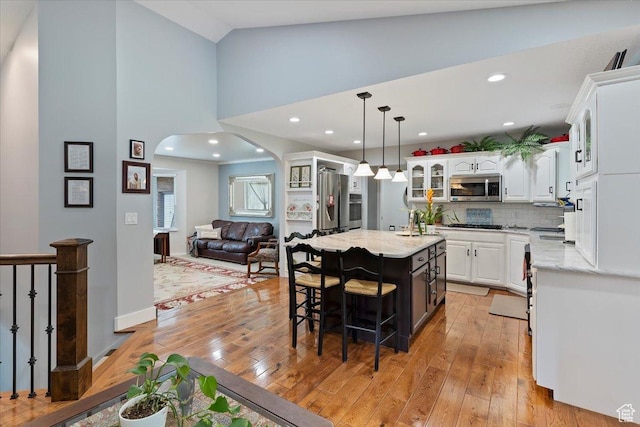 3272 N 175 W, North Ogden, UT 84414 - kitchen with appliances with stainless steel finishes, arched walkways, light wood-style floors, glass insert cabinets, and recessed lighting