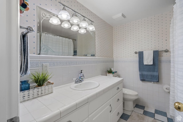 2201 E Gregson Ave, Salt Lake City, UT 84109 - bathroom featuring wallpapered walls, vanity, toilet, a wainscoted wall, and tile walls