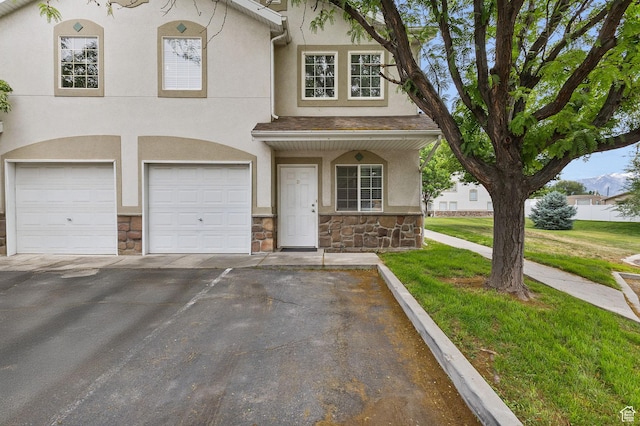 3709 S Angelico Ct Unit D, West Valley City, UT 84119 - townhome / multi-family property with stone siding, a garage, driveway, stucco siding, and a front lawn