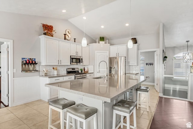 5617 W High Spirit Ct, Herriman, UT 84096 - kitchen with appliances with stainless steel finishes, white cabinetry, tasteful backsplash, vaulted ceiling, and wainscoting