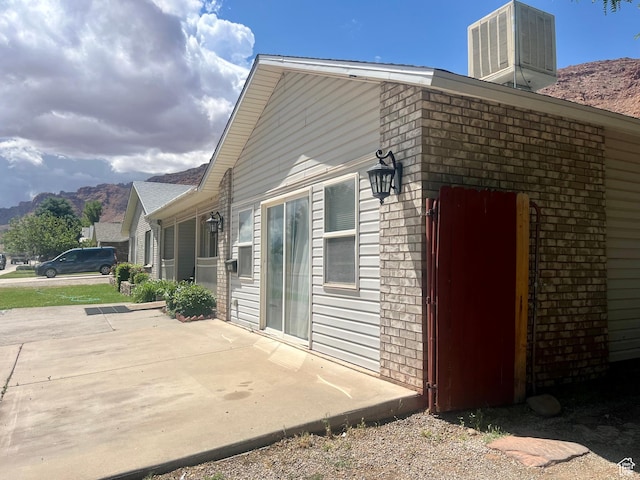 766 Huntridge Dr, Moab, UT 84532 - view of side of home featuring central AC unit, a patio area, a mountain view, and brick siding
