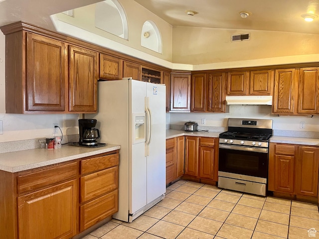 766 Huntridge Dr, Moab, UT 84532 - kitchen with stainless steel gas range, under cabinet range hood, white refrigerator with ice dispenser, light tile patterned flooring, and brown cabinets