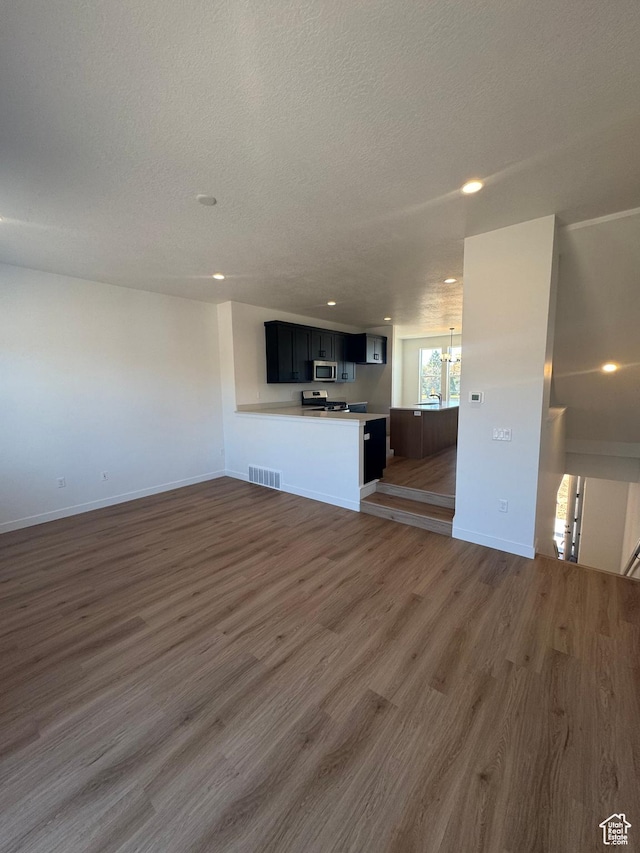 1650 N Main St N Unit 126, Layton, UT 84041 - unfurnished living room featuring wood finished floors, a chandelier, a textured ceiling, recessed lighting, and baseboards
