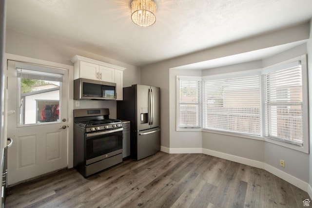 1779 E Ramona Ave S, Salt Lake City, UT 84108 - kitchen with appliances with stainless steel finishes, baseboards, white cabinetry, wood finished floors, and a chandelier