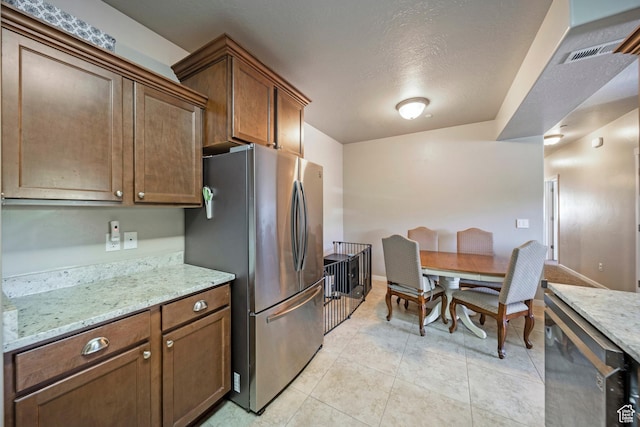 107 E Jordan Blvd Unit 506, Saratoga Springs, UT 84045 - kitchen featuring freestanding refrigerator, light stone countertops, light tile patterned flooring, baseboards, and a textured ceiling