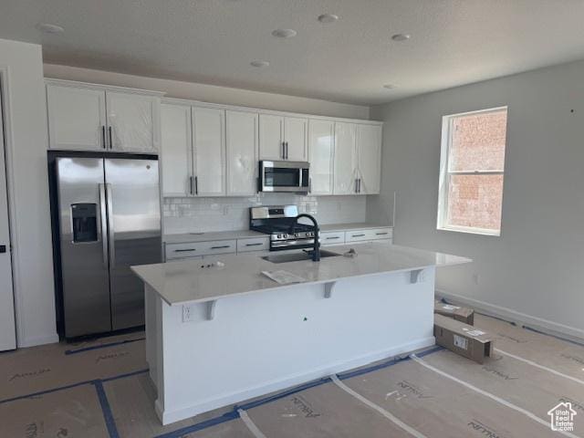 4063 W 2025 S Unit 39, Taylor, UT 84401 - kitchen featuring appliances with stainless steel finishes, a sink, backsplash, an island with sink, and light countertops
