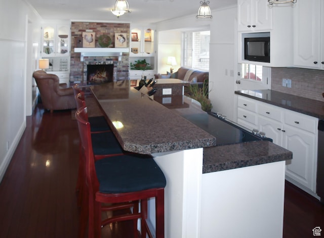 975 S Canyon Breeze E, Draper, UT 84020 - kitchen featuring open floor plan, dark countertops, dark wood-style floors, white cabinets, and a fireplace
