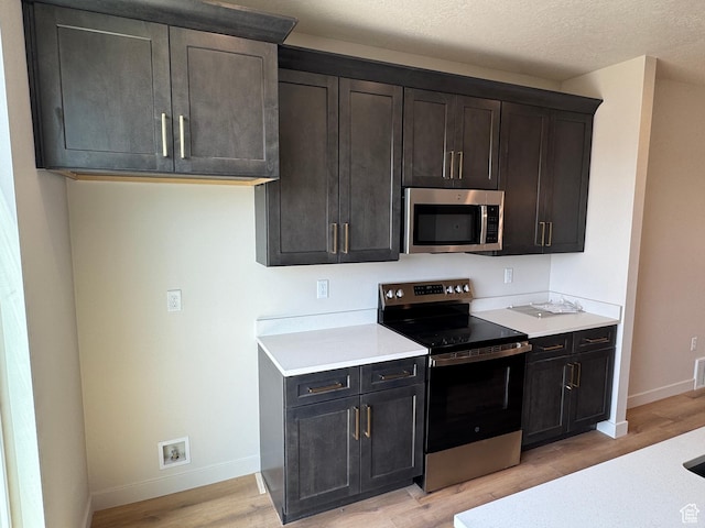 1650 N Main St N Unit 125, Layton, UT 84041 - kitchen with appliances with stainless steel finishes, light wood-style floors, light countertops, and dark brown cabinetry