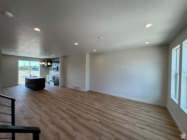 1650 N Main St N Unit 125, Layton, UT 84041 - unfurnished living room featuring a textured ceiling, wood finished floors, and recessed lighting