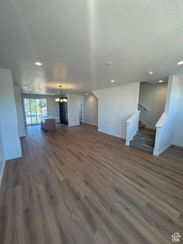 1650 N Main St N Unit 125, Layton, UT 84041 - unfurnished living room with a chandelier, dark wood-type flooring, a textured ceiling, recessed lighting, and stairs