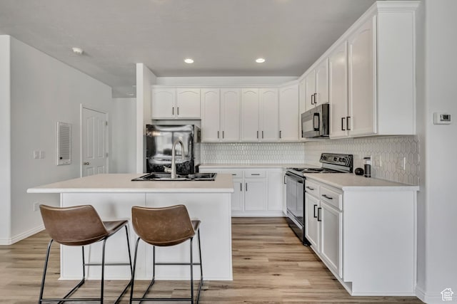 7284 S Brittany Park Ave, West Jordan, UT 84084 - kitchen featuring electric stove, freestanding refrigerator, a kitchen bar, a sink, and an island with sink