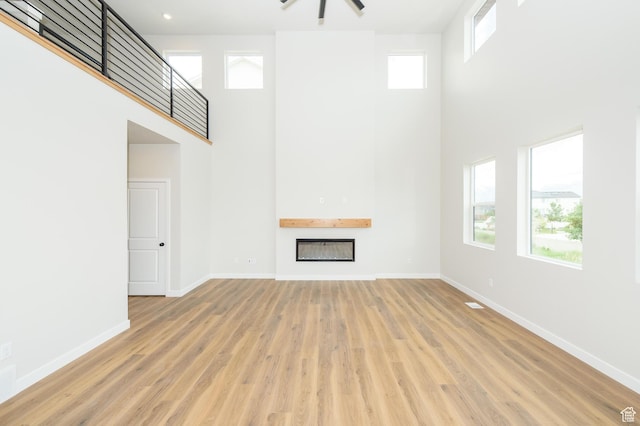 166 N Husker Ln, Saratoga Springs, UT 84045 - unfurnished living room with a high ceiling, a fireplace, baseboards, and wood finished floors