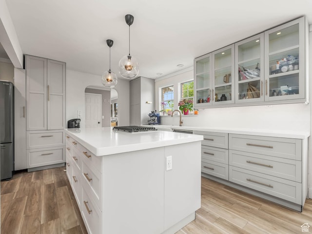 167 N 750 E, Orem, UT 84097 - kitchen featuring arched walkways, a center island, stainless steel appliances, light wood finished floors, and glass insert cabinets
