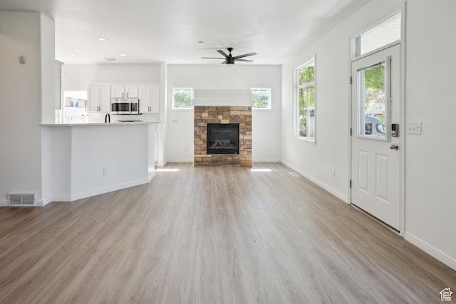 11411 S Oakmond Rd, South Jordan, UT 84009 - unfurnished living room featuring a ceiling fan, light wood-style floors, a stone fireplace, baseboards, and recessed lighting