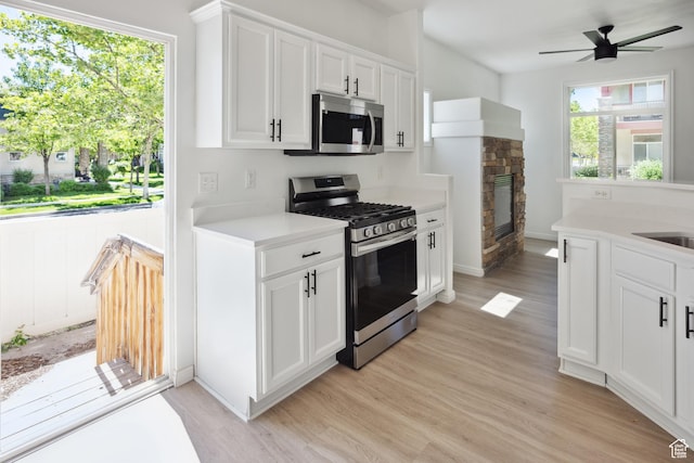11411 S Oakmond Rd, South Jordan, UT 84009 - kitchen featuring appliances with stainless steel finishes, light wood finished floors, light countertops, and a fireplace