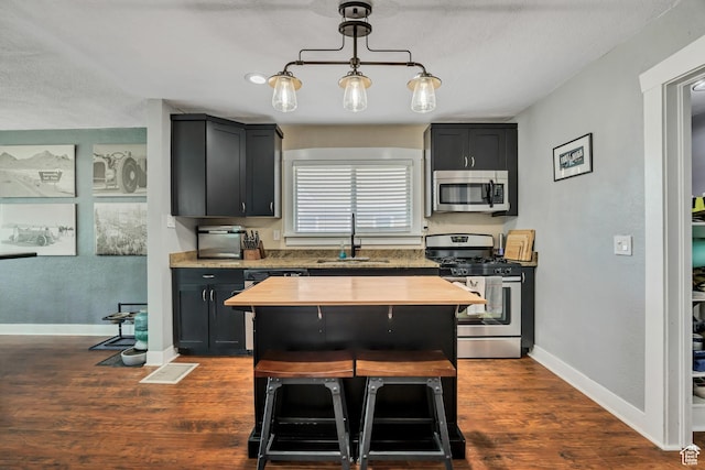 763 E Spring View Dr, Millcreek, UT 84106 - kitchen with appliances with stainless steel finishes, dark cabinetry, dark wood-type flooring, and hanging light fixtures