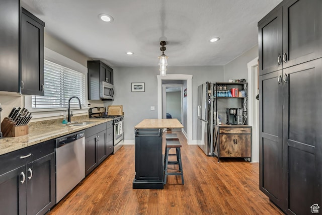 763 E Spring View Dr, Millcreek, UT 84106 - kitchen featuring appliances with stainless steel finishes, recessed lighting, light stone counters, wood finished floors, and a breakfast bar area