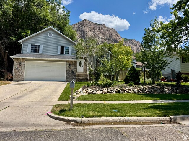 574 N Jackson Ave, Ogden, UT 84404 - view of front of home featuring an attached garage, concrete driveway, stone siding, and a front lawn