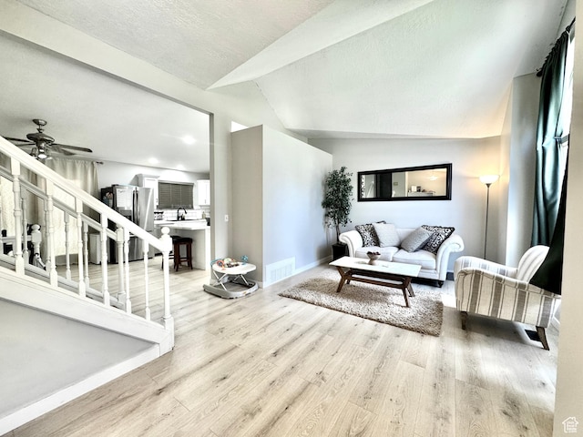 574 N Jackson Ave, Ogden, UT 84404 - living room with light wood-style floors, vaulted ceiling, baseboards, a ceiling fan, and stairs