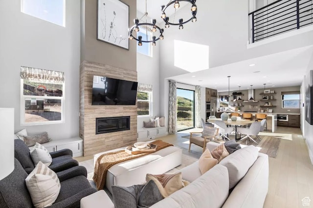 5877 N Canyon Rim Rd Unit 623, Lehi, UT 84043 - living room featuring a towering ceiling, a tiled fireplace, a chandelier, and light wood-style floors