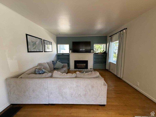 229 N Carbon Ave, Price, UT 84501 - living room featuring healthy amount of natural light, a brick fireplace, wood finished floors, and baseboards