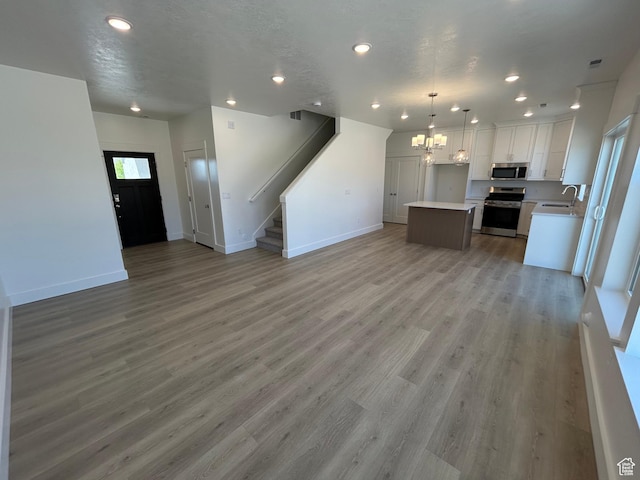 554 N 800 W, Smithfield, UT 84335 - unfurnished living room with a sink, a chandelier, baseboards, stairs, and recessed lighting