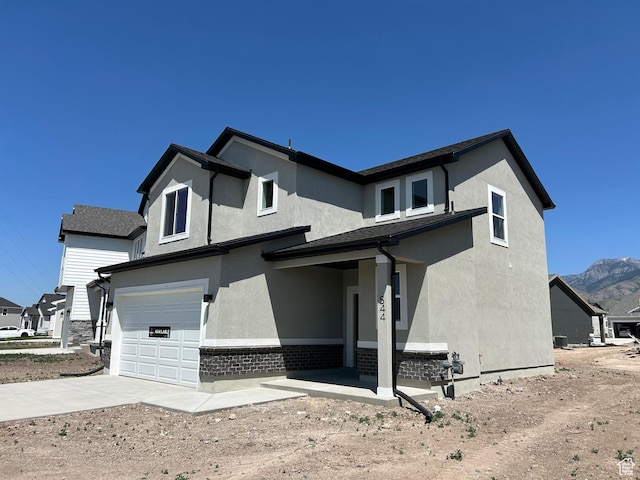 554 N 800 W, Smithfield, UT 84335 - rear view of house with a garage, concrete driveway, stucco siding, and a mountain view