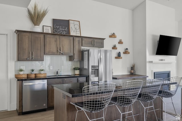 1871 S 1030 W, Orem, UT 84058 - kitchen with appliances with stainless steel finishes, a sink, dark countertops, light wood-style flooring, and a kitchen breakfast bar