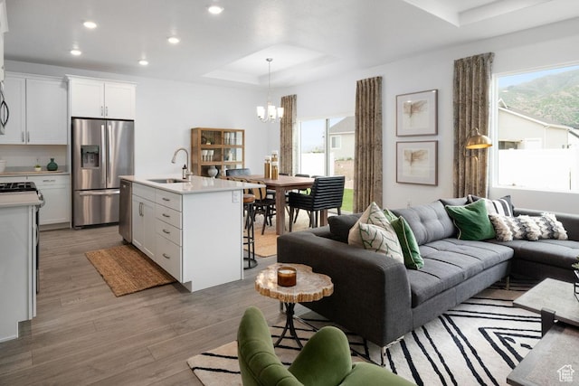 4111 W 1575 S Unit 118, Ogden, UT 84404 - living area featuring a chandelier, healthy amount of natural light, a raised ceiling, recessed lighting, and light wood-type flooring