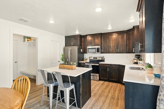 2124 S 1490 W, Wellsville, UT 84339 - kitchen with appliances with stainless steel finishes, light wood-type flooring, a kitchen bar, a kitchen island, and dark brown cabinetry