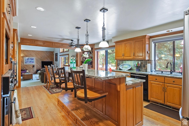 12144 S Mountain Shadow Rd, Sandy, UT 84092 - kitchen featuring a sink, a kitchen island, light wood-style floors, a breakfast bar, and wooden walls